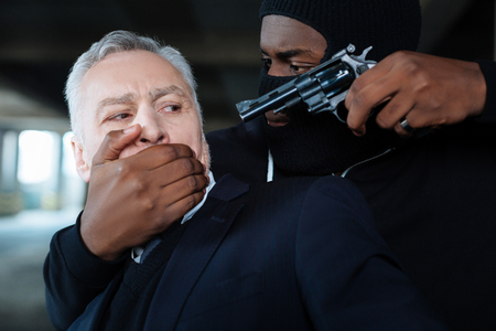 Dangerous angry kidnapper threatening a businessmanの写真素材