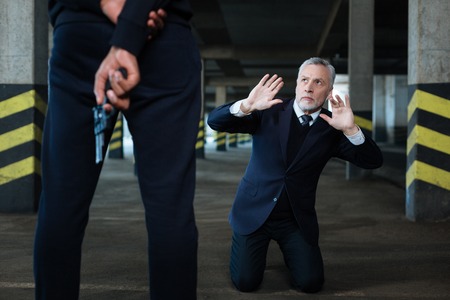 Frightened unhappy businessman looking at the criminalの写真素材