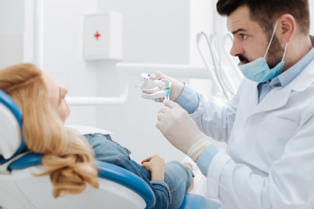 Wonderful caring dentist explaining specifics of dental hygieneの写真素材