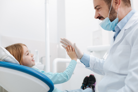 Cheerful great dentist giving his little patient a high fiveの写真素材