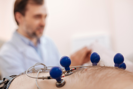 Experienced cardiologist attaching sensors to patients chest