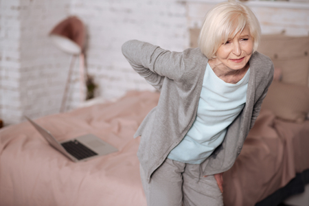 Elderly woman standing with backache