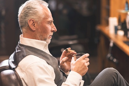 Sophisticated man sitting and enjoying atmosphere in the barbershop