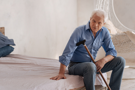 Serious elderly man sitting alone in the roomの写真素材