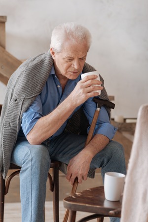 Cheerless aged man holding a cupの写真素材