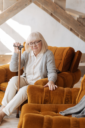 Nice cheerless woman sitting near the empty armchairの写真素材