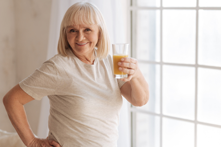 Joyful happy woman holding a glass with orange juiceの写真素材