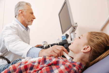 Handsome practitioner using ultrasound transducer in the hospitalの写真素材