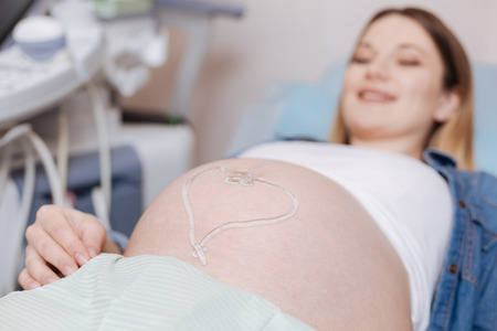 Delightful pregnant woman lying on the medical couch in the hospital