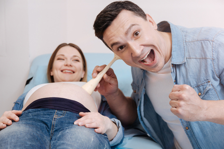 Joyful man listening to the fetus heart beating in the clinicの写真素材