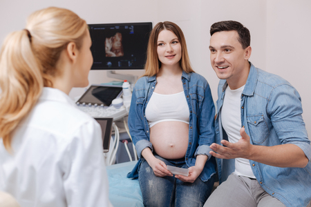 Friendly medic enjoying appointment with future parents in the clinicの写真素材