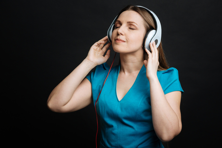 Delightful young woman using headphones in the studioの写真素材