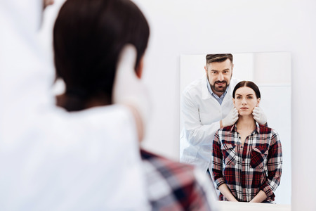 Serious beautiful woman looking at her reflectionの写真素材