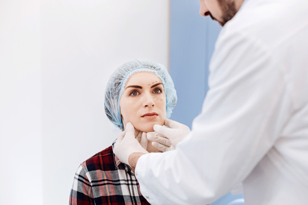 Serious young woman having an appointment with a plastic surgeonの写真素材
