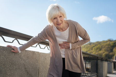Retired woman feeling pain during the promenadeの写真素材