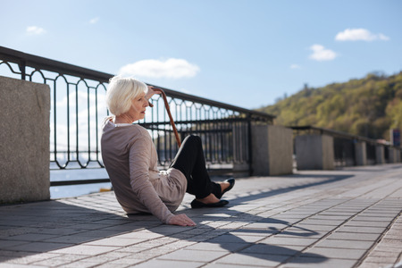 Weak woman sitting on the ground in the streetの写真素材