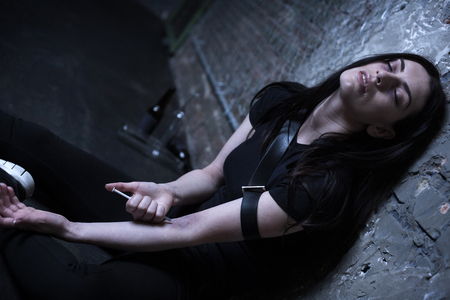 Frustrated junkie using syringe full of drugs outdoorsの写真素材