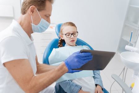 Bright attentive dentist showing updates on patients progressの写真素材