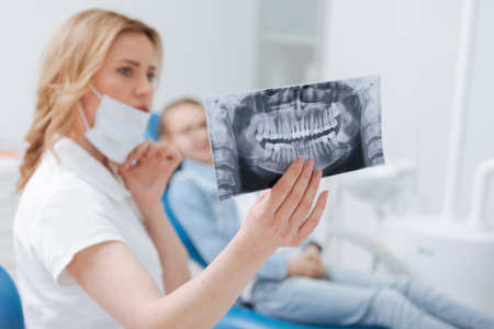 Neat observant dentist holding up an xrayの写真素材