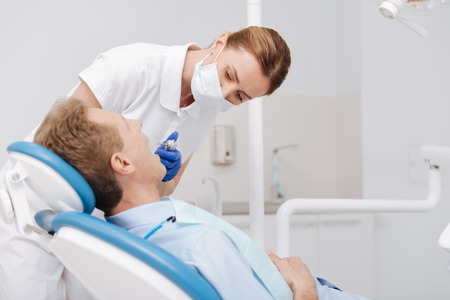 Young neat dentist being very attentiveの写真素材