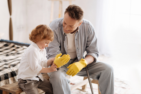 Funny kind helping his daddy to put on glovesの写真素材