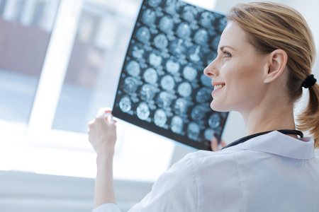 Confident neurosurgeon analyzing roentgen brain results at the laboratoryの写真素材