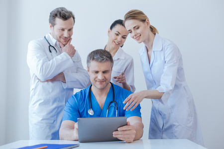 Delighted medics enjoying new digital gadget at workの写真素材