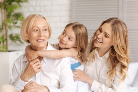 Cheerful amused mother and child looking at the grandmother
