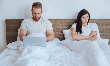 Couple ignoring each other in bed