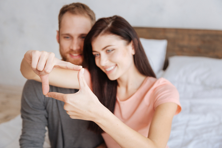 Millennial couple framing faces with handsの写真素材