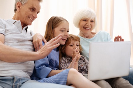 Friendly smart children using laptop for calling parents