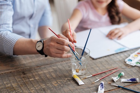 Hands of daughter and her father washing brushesの写真素材