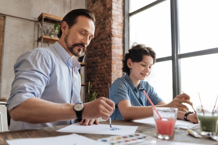 Father and his son spending time together while paintingの写真素材