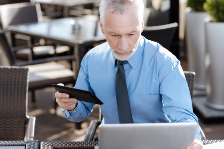 Attentive man using hid gadgets while preparationの写真素材