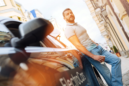 Handsome man posing near his new electric carの写真素材