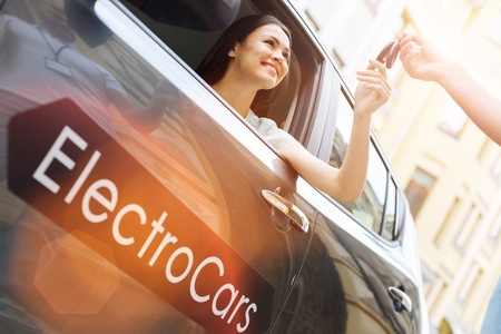 Male hand giving car keys to a joyful womanの写真素材