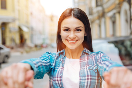 Pleasant smiling woman holding her boyfriends handsの写真素材