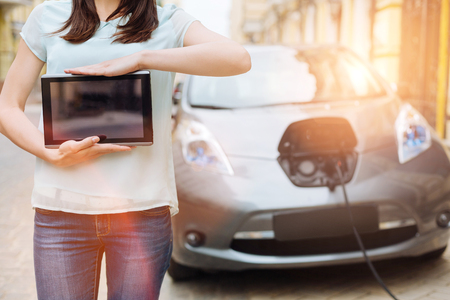 Female holding a tablet in front of her carの写真素材