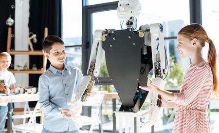 Girl and boy holding hands of a big human robot