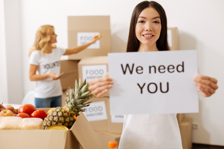 Open minded cheerful woman holding a poster promoting charity