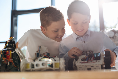 Merry boy observing his friend working on new robot