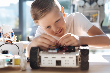 Adorable kid fixing wires in robotic vehicleの写真素材