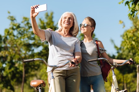 Positive senior woman making photos with her pretty granddaughterの写真素材