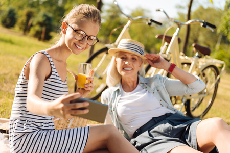 Positive grandmother and teenager girl enjoying picnic outdoorsの写真素材