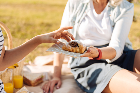 Pleasant senior woman giving her granddaughter a freshly baked croissantの写真素材