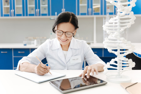 Joyful pleasant woman writing in her notebookの写真素材