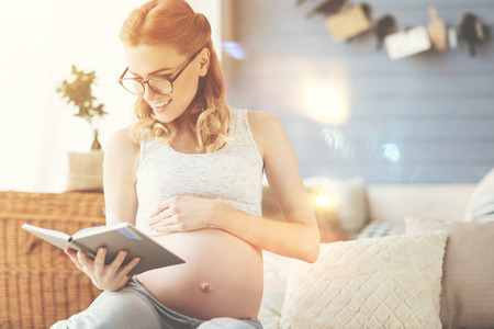 Young pregnant woman reading a bookの写真素材