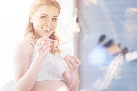 Pleasant pregnant woman eating yoghurtの写真素材