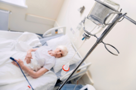 Aged ailing woman receiving medication through a dripの写真素材