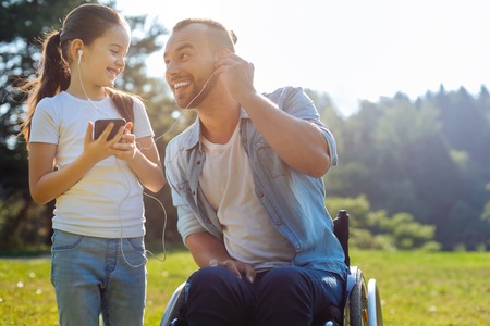 Father with mobility impairment listening to music with daughterの写真素材